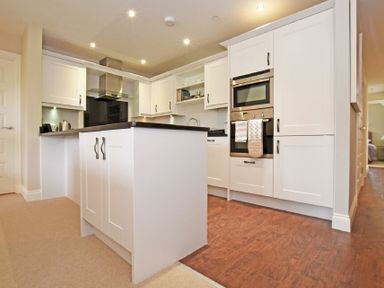 A kitchen with white cabinets a central island and built in stainless steel oven at Sandpiper Bamburgh