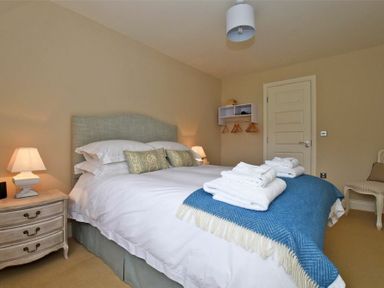 A bedroom with a double bed bedside tables with lamps and a chair at Sandpiper Bamburgh