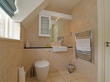 A bathroom with a toilet sink mirror towel rack and window at Sandpiper Bamburgh