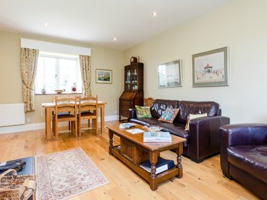 A living room with wooden dining table chairs leather sofa armchair coffee table and wall art at Mid Cote in Shoreston near Bamburgh