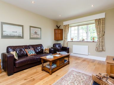 A living room with brown leather sofa and chair wooden coffee table and window with patterned curtains at Mid Cote Shoreston near Bamburgh