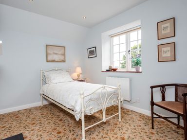 A bedroom with a single bed a chair a window and framed pictures on the walls at Mid Cote in Shoreston near Bamburgh
