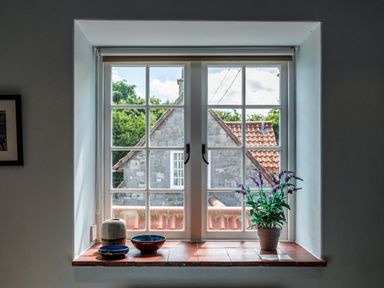A window with potted plant and ceramic bowls on the sill at Mid Cote Shoreston near Bamburgh
