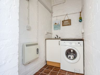 A laundry room with a washing machine sink and heater at Mid Cote Shoreston near Bamburgh