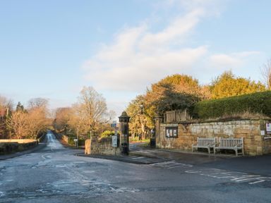 A road intersection with stone walls two benches and trees at Nurse's Cottage in Alnwick