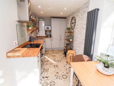 A kitchen with wooden countertops and patterned floor tiles at Old Stable Cottage in Alnmouth