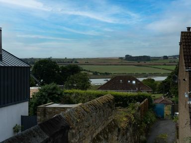 A view of a rural landscape with houses trees a river and fields at Pilots Rest in Alnmouth