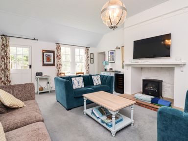 A living room with blue sofas a coffee table a wall mounted tv and a fireplace at Salty Dog in Bamburgh