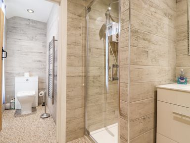 A bathroom with a toilet a glass shower enclosure and a sink with soap at Salty Dog in Bamburgh