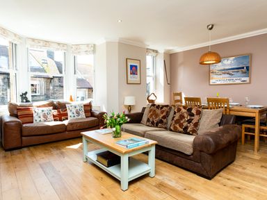 A living room with two sofas a coffee table with flowers and a dining table with chairs at Upper Alnbank in Alnmouth