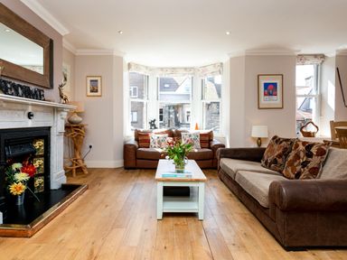 A living room with two brown sofas a white coffee table with flowers and a fireplace at Upper Alnbank in Alnmouth