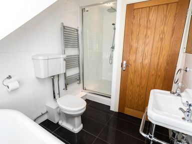 A bathroom with a toilet bidet sink wooden door and a glass shower at Upper Alnbank in Alnmouth