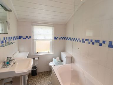 A bathroom with a sink mirror toilet bathtub and window at Sand Dune Cottage in Bamburgh