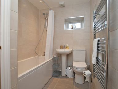 A bathroom with a bathtub shower combination a pedestal sink a toilet and a towel rack at Schooner Court No1 in Alnmouth