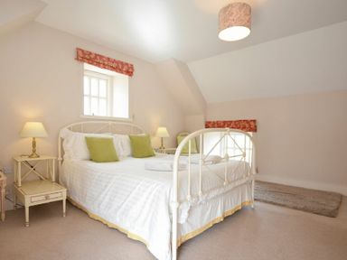 A bedroom with a white bed and green pillows with two lamps on bedside tables at Sea Breeze in Newton-by-the-Sea
