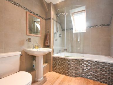A bathroom with a toilet a pedestal sink a bathtub with shower and a window at Sea Breeze in Newton-by-the-Sea