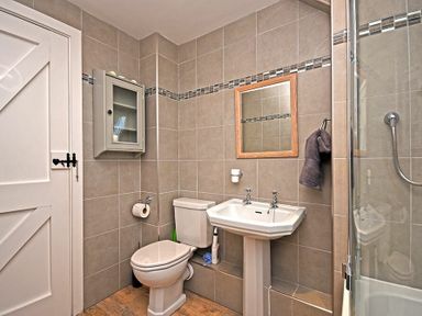A bathroom with a toilet sink shower and cabinet at Sea Breeze in Newton-by-the-Sea