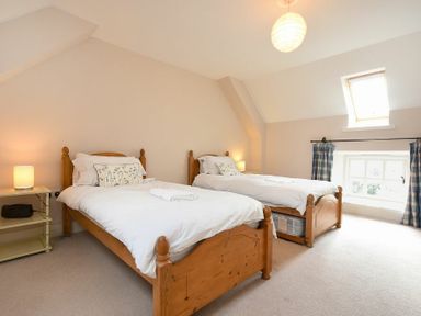 A bedroom with two single wooden beds white bedding and two lamps at Sea Breeze in Newton-by-the-Sea