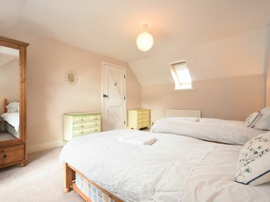 A bedroom with two single beds a green chest of drawers and a wooden wardrobe at Sea Breeze in Newton-by-the-Sea
