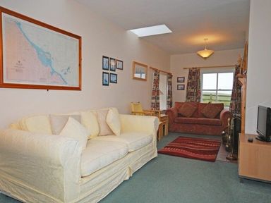 A living room with two sofas a red rug a wood stove and a television at Snook Point Cottage in Newton-by-the-Sea