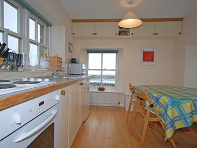 A kitchen with a stove sink countertop microwave and table with chairs at Snook Point Cottage Newton-by-the-Sea