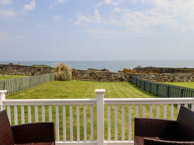 A backyard with grass and wooden fences overlooking the sea at South Cottage Howick in Craster