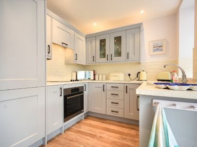 A kitchen with gray cabinets a black oven a microwave kettle and toaster on the counter at Ty y Mor in Seahouses
