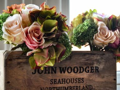 A wooden box with flowers inside and text john woodger seahouses northumberland at Ty y Mor in Seahouses