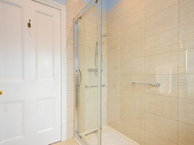 A shower enclosure with glass doors and tiled walls at Ty y Mor in Seahouses