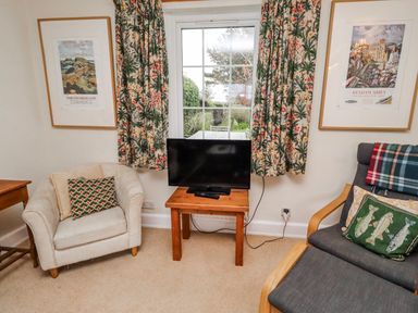 A living room with a television and seating at St Marys Cottages No4 Low Newton-by-the-Sea