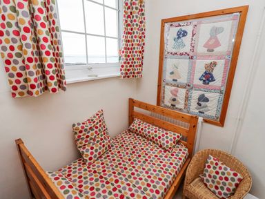 A bedroom with a bed, quilt on the wall and window at St Marys Cottages No4 Low Newton-by-the-Sea