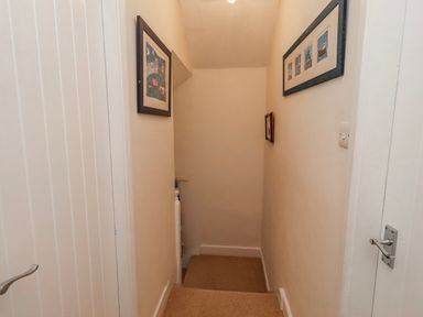 A hallway with a staircase and framed pictures at St Marys Cottages No4 Low Newton-by-the-Sea