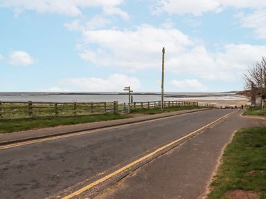 A road with a fence and a signpost near the beach at St Marys Cottages No4 Low Newton-by-the-Sea