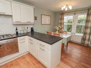 A kitchen with a stove, sink, and dining area at Sugar Sands in Longhoughton