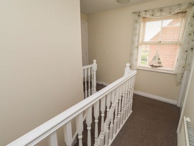 A hallway with a stair railing and a window at Sugar Sands in Longhoughton