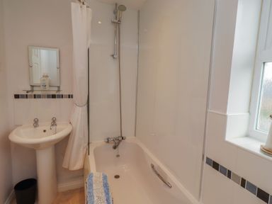 A bathroom with a bathtub and sink at Sugar Sands in Longhoughton