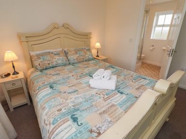 A bedroom with a bed and bathroom view at Sugar Sands Longhoughton