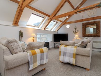 A living room with two sofas facing a television and wooden beams on the ceiling at The Boathouse (Seahouses) in Seahouses