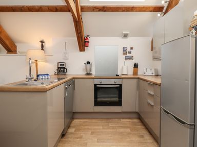 A kitchen with wooden beams a sink a coffee maker an oven a refrigerator and various kitchen utensils at The Boathouse (Seahouses) in Seahouses