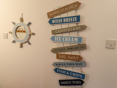 A wall with nautical-themed directional signs and a ship wheel mirror at The Boathouse (Seahouses) in Seahouses
