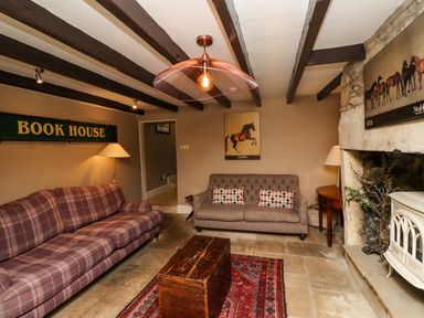 A living room with two sofas wooden chest coffee table stone fireplace and framed horse pictures at The Book House in Warkworth