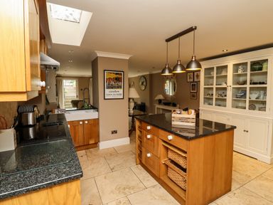 A kitchen with an island and white cabinets with glass doors at The Book House in Warkworth