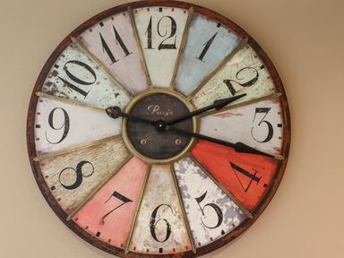 A wall clock with multicolored numbered segments and black clock hands at The Book House in Warkworth