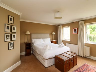 A bedroom with a bed white bedding and two windows at The Book House in Warkworth