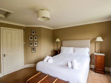 A bedroom with a double bed white linens bedside tables with lamps and framed pictures on the wall at The Book House in Warkworth