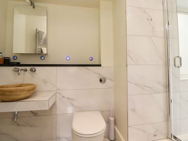 A bathroom with a toilet sink mirror and a shower at The Book House in Warkworth