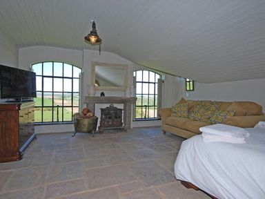 A living room with large windows a fireplace a sofa and a television at The Huffy House in Alnmouth