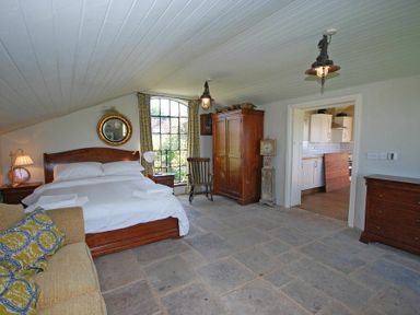 A bedroom with a wooden bed sofa armchair wardrobe and chest of drawers at The Huffy House in Alnmouth