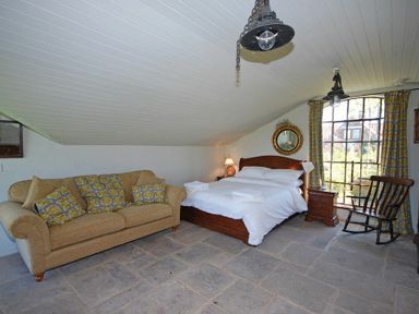 A bedroom with a bed sofa rocking chair and window at The Huffy House in Alnmouth