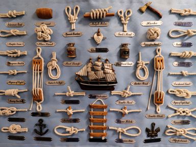 A display board with various types of knots and nautical items including a model ship and lanterns